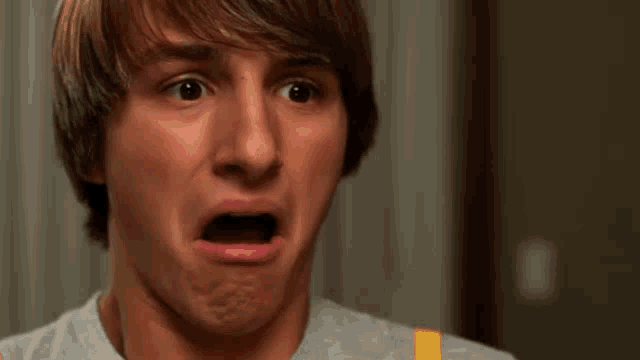 a young man with his mouth open is making a surprised face .