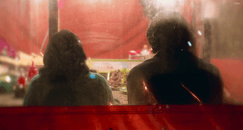 a blurry picture of a man and woman behind a red curtain with the word king on the bottom right