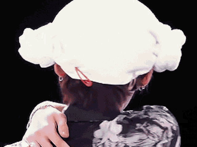 a woman is wearing a white hat with a red clip on it