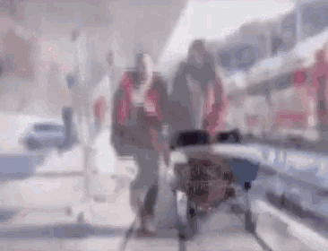 a blurry picture of a man pushing a woman in a wheelchair in a store .
