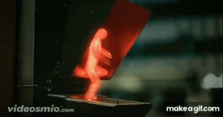 a red pedestrian crossing light with a person walking in the background