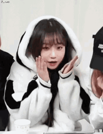 a girl wearing a black and white hoodie is sitting at a table .