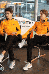 two men sit in front of a chrome sign