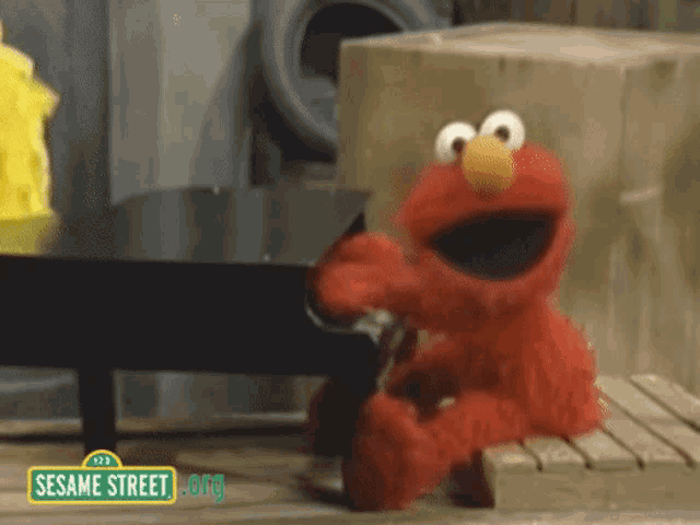 elmo from sesame street is sitting on a wooden plank