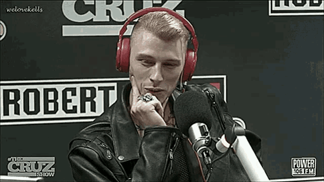 a man wearing headphones is sitting in front of a microphone in a radio station .