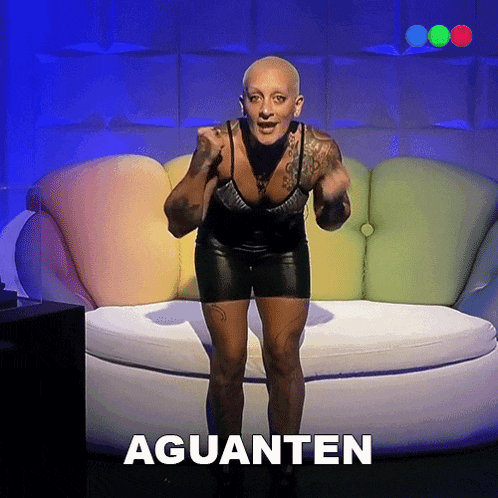 a woman standing in front of a colorful couch with the word aguanten written on the bottom