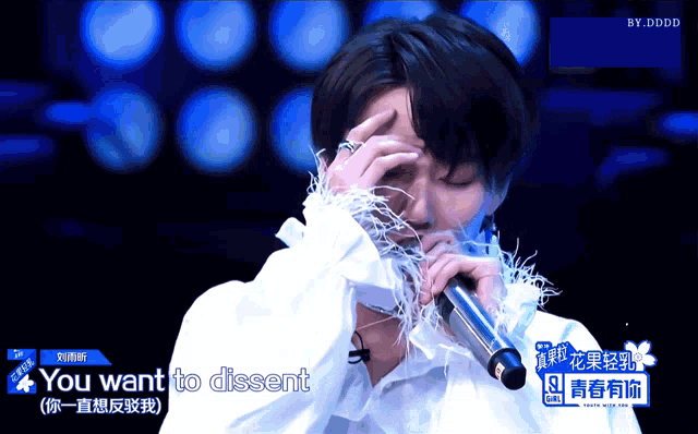 a man singing into a microphone with the words " you want to dissent " behind him