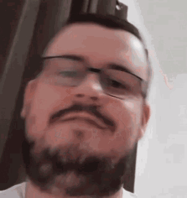 a close up of a man with a beard and glasses making a funny face .