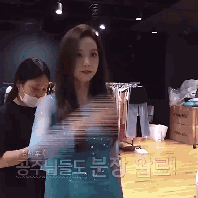 a woman in a blue dress is standing next to another woman in a mask