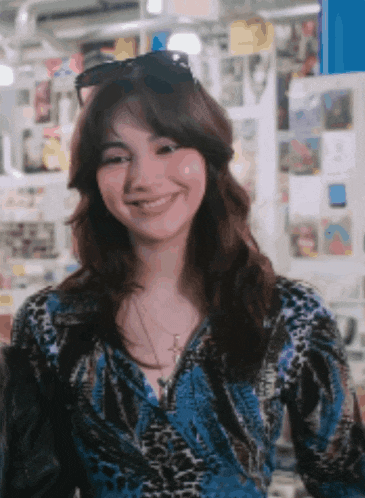 a woman wearing sunglasses and a blue shirt is smiling for the camera