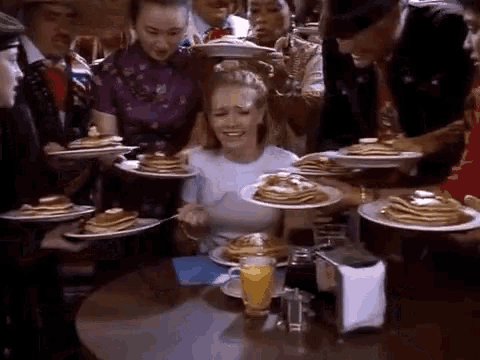 a woman sits at a table surrounded by pancakes