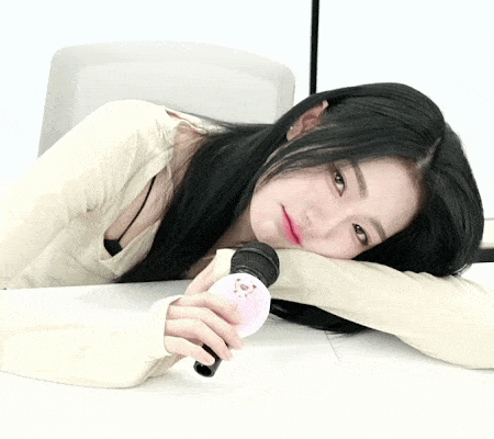 a woman with long black hair is laying on the floor holding a microphone