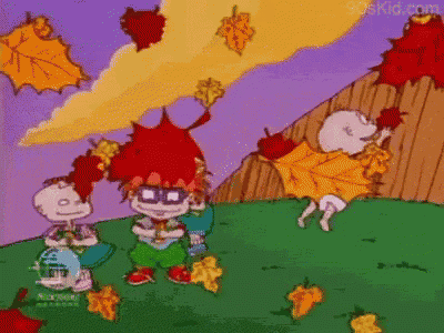 a group of rugrats characters are standing in a field with leaves falling around them .