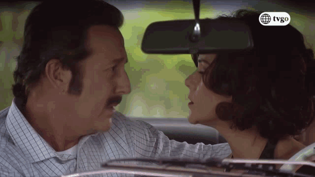 a man and woman are kissing in a car with a tvgo logo on the bottom