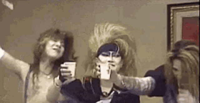 a group of people are standing next to each other in a room holding cups .
