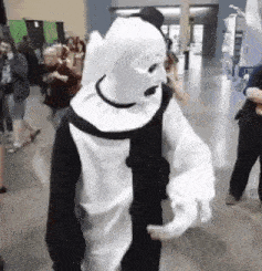 a man in a black and white clown costume is walking in a hallway .