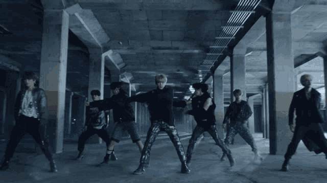 a group of young men are dancing in a dark hallway
