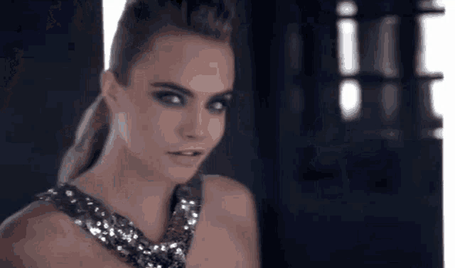 a woman in a sequined dress is standing in front of a window looking at the camera .