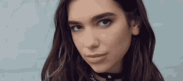 a close up of a woman wearing a choker and looking at the camera