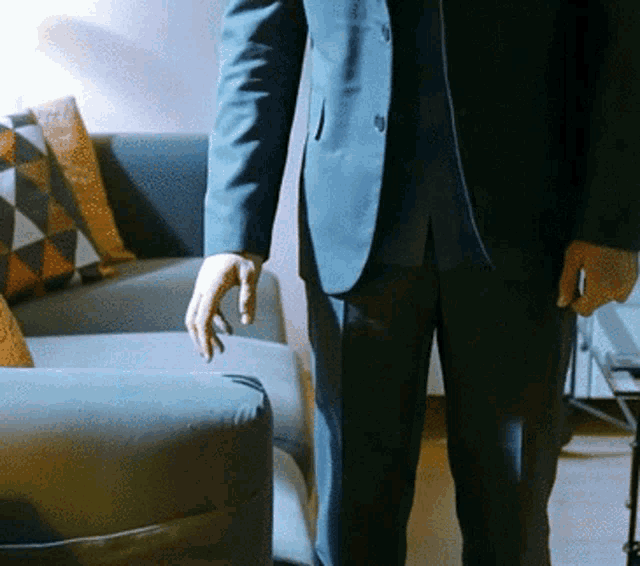 a man in a suit standing next to a couch