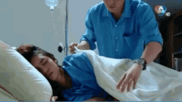 a man is standing next to a woman laying in a hospital bed
