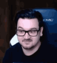 a man wearing glasses and a mustache is sitting in a blue chair .