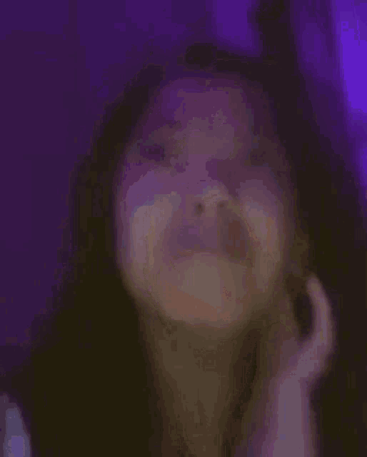 a blurry picture of a woman covering her face with her hand .