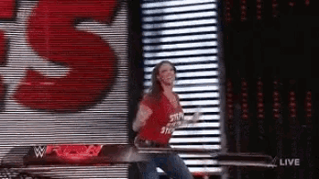 a woman wearing a red shirt that says ' smackdown ' on it is dancing on a stage .