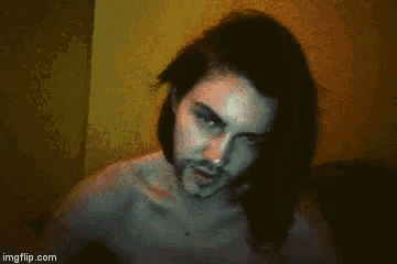 a man with long hair and a beard is smiling in a dark room
