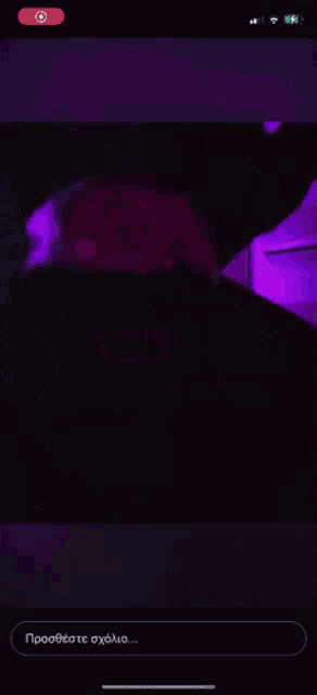 a phone screen shows a silhouette of a person standing in front of a computer with purple lights behind them