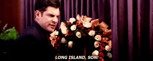 a man is standing in front of a wreath of flowers and says `` long island , son ! ''