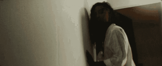 a woman leaning against a wall in a room