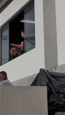 a group of men looking out of a window with a black tarp on the side