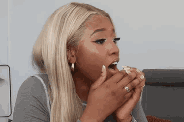 a woman with blonde hair and a ring on her finger is eating something