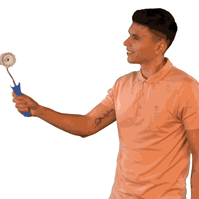 a man in a pink polo shirt is holding a roller