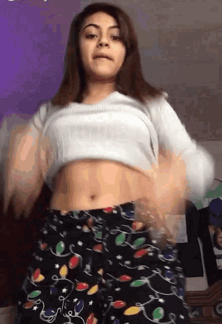 a girl wearing a white top and christmas lights pajamas