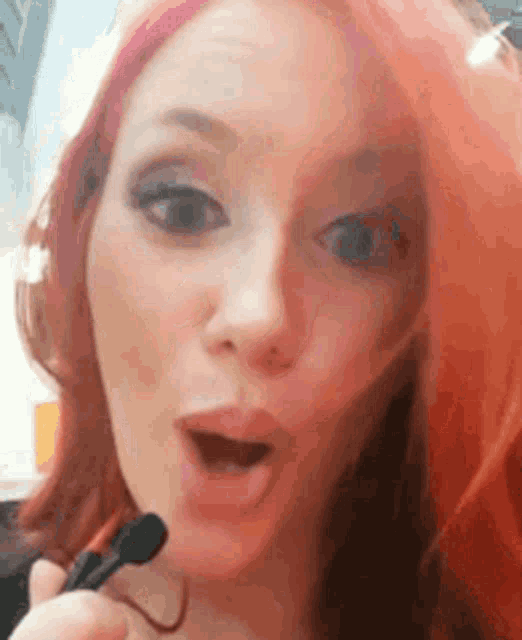 a close up of a woman with pink hair holding a microphone .