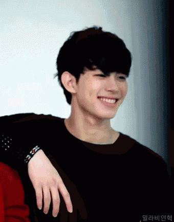 a young man wearing a black shirt is smiling with his hand on his shoulder