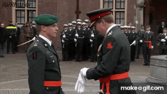two men in military uniforms are standing next to each other with a make a gif.com link in the corner