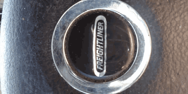 a close up of a freightliner wheel cap on a black surface
