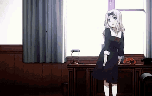 a girl in a black dress stands in front of a window