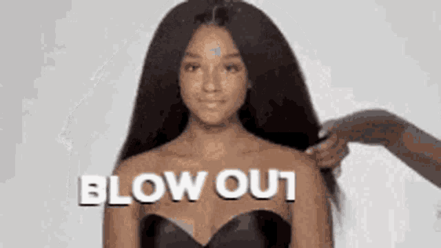 a woman in a black dress is getting her hair blown out by another woman .