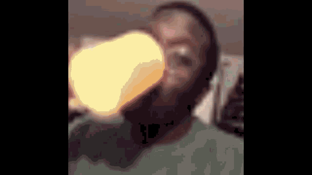 a man in a green shirt is drinking from a yellow cup .