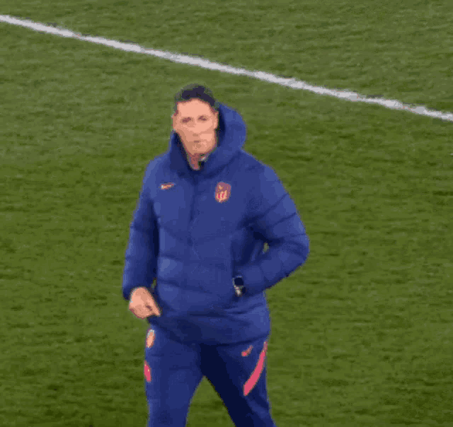 a man in a blue nike jacket stands on a field