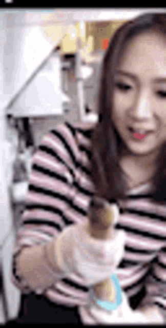 a woman in a striped shirt is holding a cone in her hands .