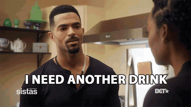 a man says i need another drink while talking to a woman in a kitchen