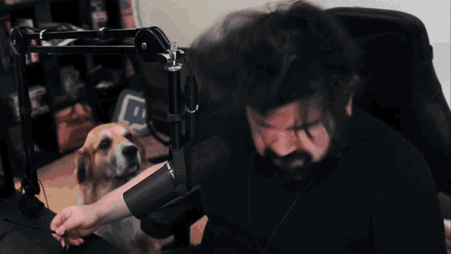 a man and a dog are sitting in front of a microphone with a twitch logo in the background