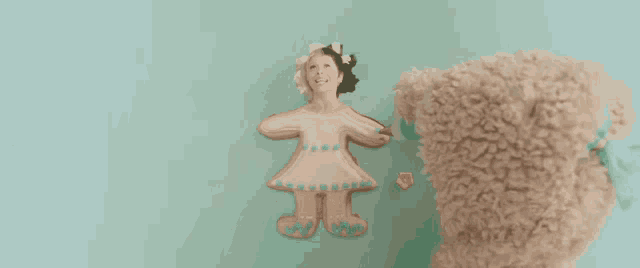 a teddy bear is standing next to a cookie that looks like a girl