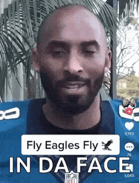 a man with a beard is wearing a blue eagles jersey and says fly eagles fly in da face