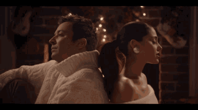 a man in a white sweater and a woman in a white dress back to back
